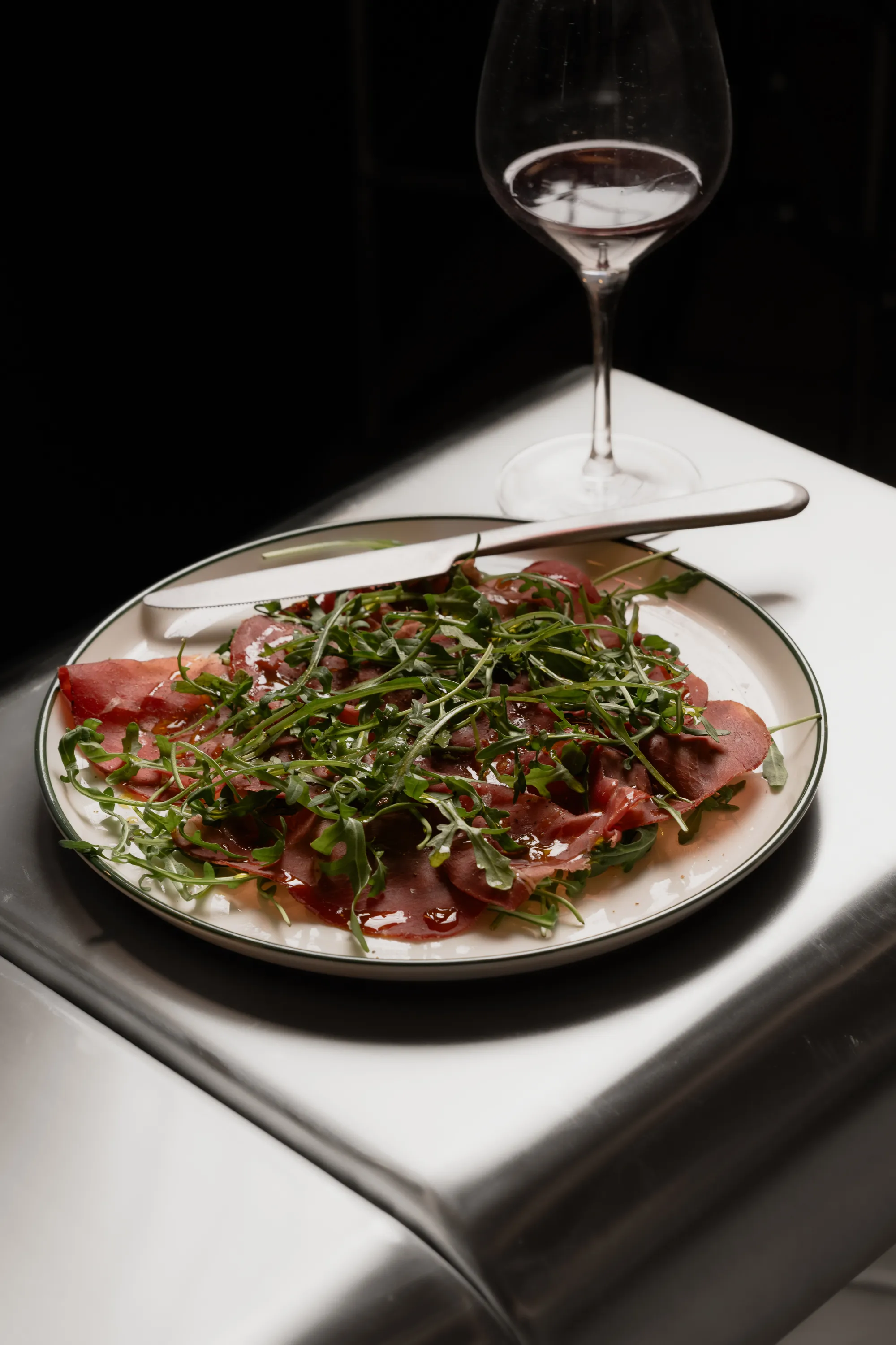 Carpaccio with rocket and a glass of wine